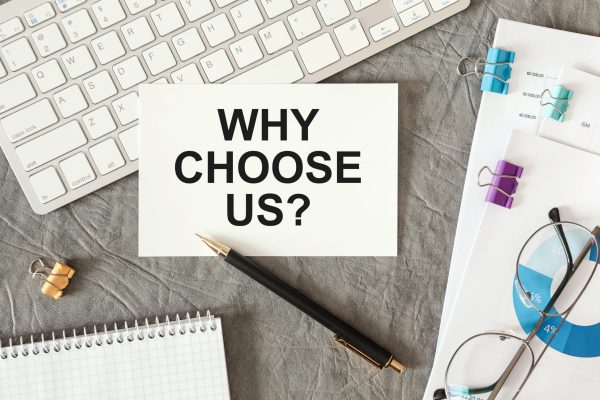 Why Choose Us is written in a document on the office desk with office accessories.